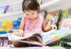 Petite fille lisant un livre dans une bibliothèque.