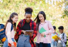trois adolescentes consultent une tablette.