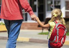 Adulte tenant un enfant par la main pour l'accompagner à l'école