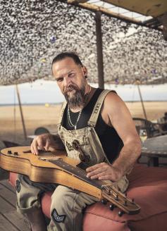 Will Barber, participant à l'émission The Voice, photographié en train de faire de la guitare sur la plage