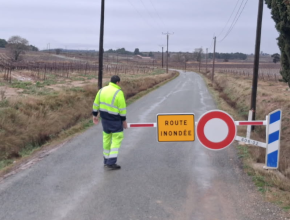 Un agent des routes barre une route inondée lors des intempéries de janvier 2026 dans l'Aude