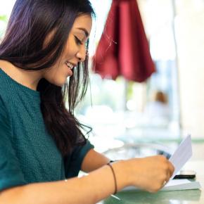 Jeune femme en train de mettre un courrier dans une enveloppe.