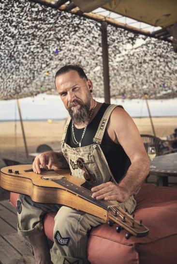 Will Barber, participant à l'émission The Voice, photographié en train de faire de la guitare sur la plage