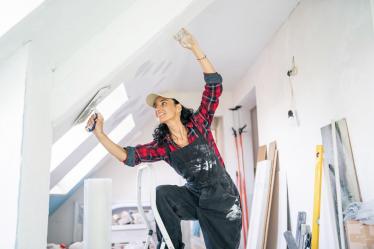 Jeune femme réalisant des travaux de rénovation, bricolage et plâtre, dans sa maison.