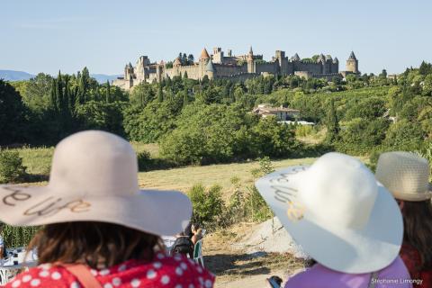deux touristes aux chapeaux devant la cité de Carcassonne