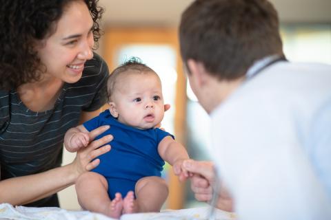 Un médecin ausculte un bébé, tenu par sa maman