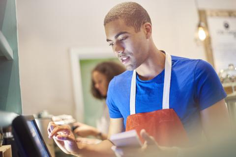 jeune travaillant à la caisse d'un restaurant