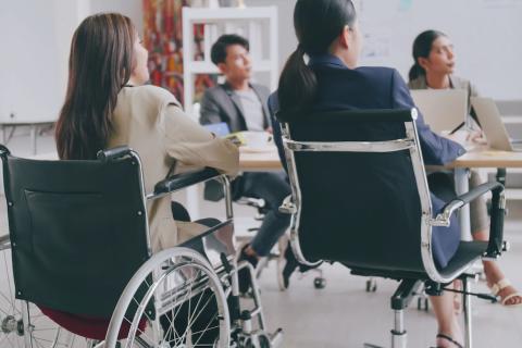 Personne en fauteuil roulant en réunion de travail avec des collègues.