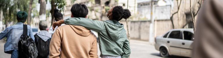 Jeunes de dos en train de marcher bras dessus, bras dessous