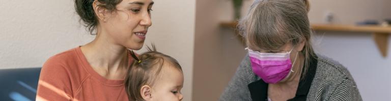 Une jeune femme réfugiée avec son enfant remplit des papiers, aidée d'une dame.