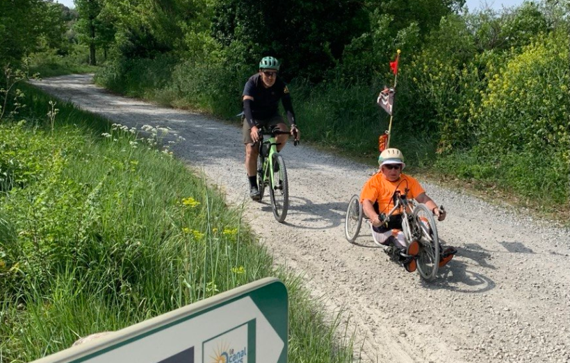 Handbikeur et cycliste circulent le long du canal du Midi.