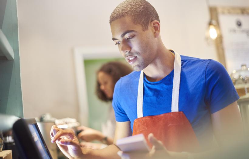 jeune travaillant à la caisse d'un restaurant