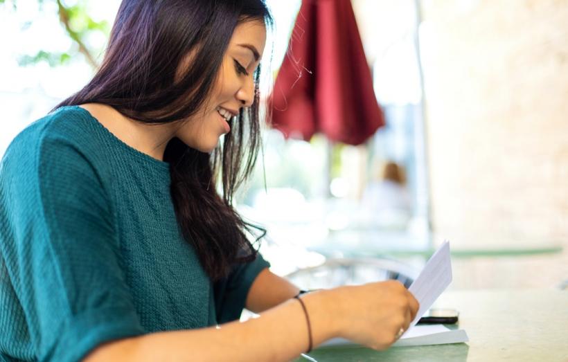 Jeune femme en train de mettre un courrier dans une enveloppe.
