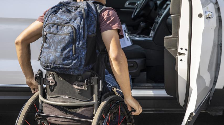 Un étudiant en fauteuil roulant monte à bord d'une voiture.