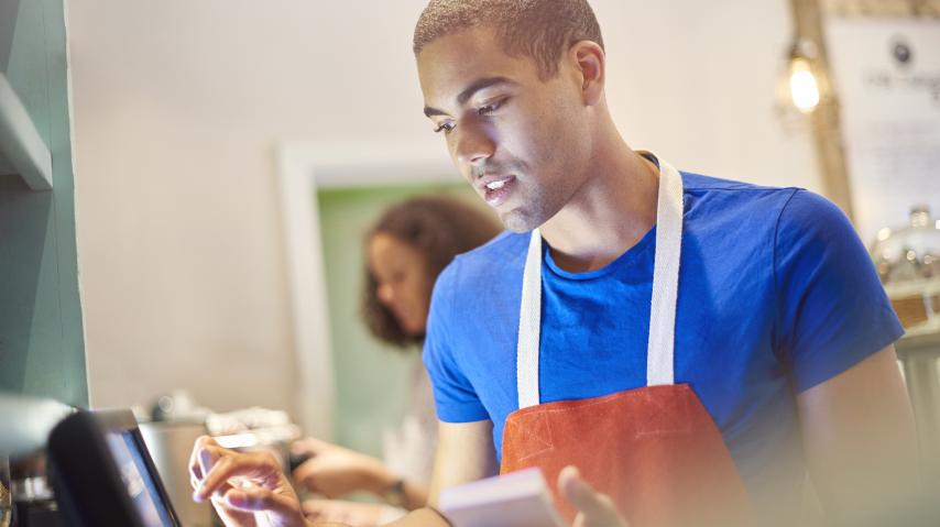 jeune travaillant à la caisse d'un restaurant