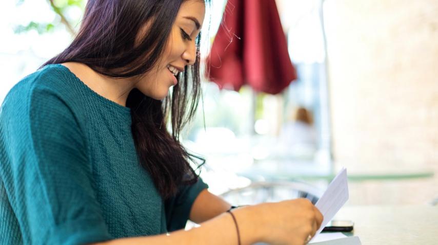 Jeune femme en train de mettre un courrier dans une enveloppe.