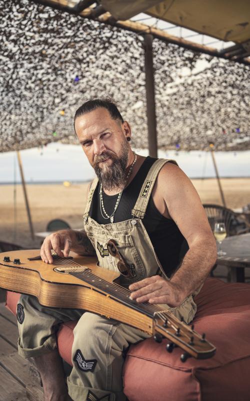 Will Barber, participant à l'émission The Voice, photographié en train de faire de la guitare sur la plage